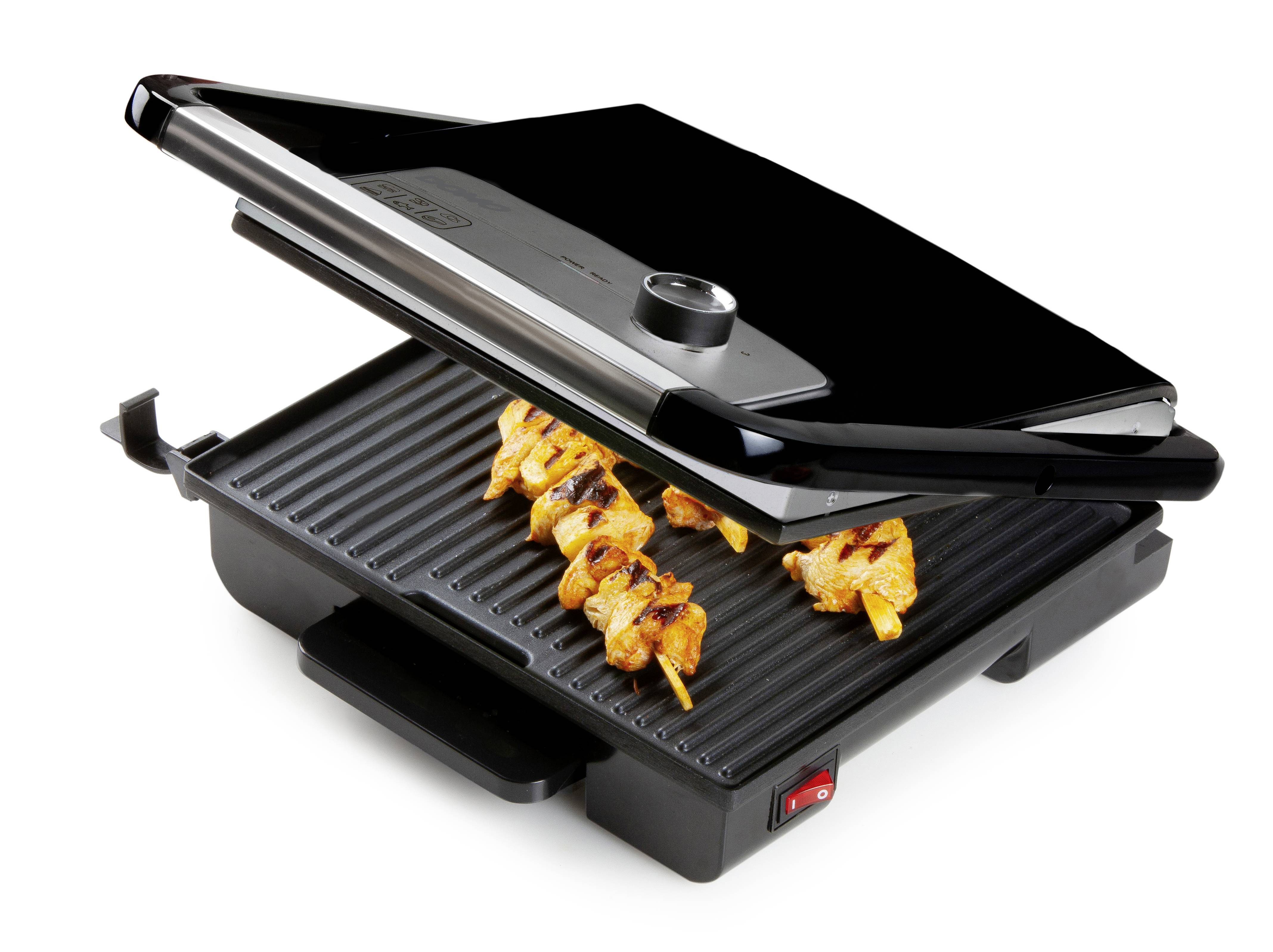 Un grill de table avec le couvercle ouvert, sur lequel grillent des brochettes de poulet. Le grill a une surface lisse, noire, et un voyant de contrôle rouge.