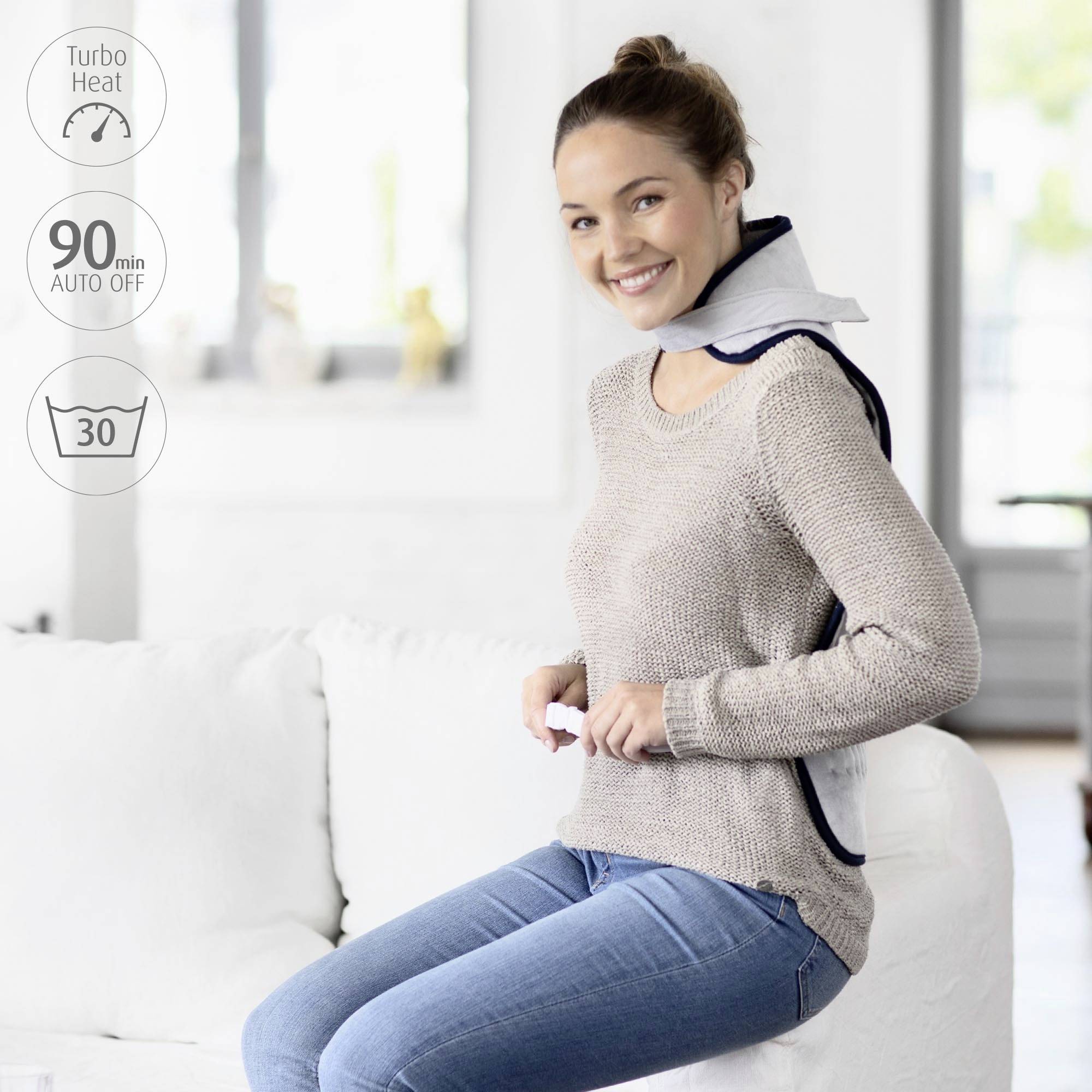 Une femme est assise sur un canapé et porte un coussin chauffant sur les épaules. Texte : 'Turbo Heat', '90 min Arrêt auto', '30'. Elle sourit de manière détendue.