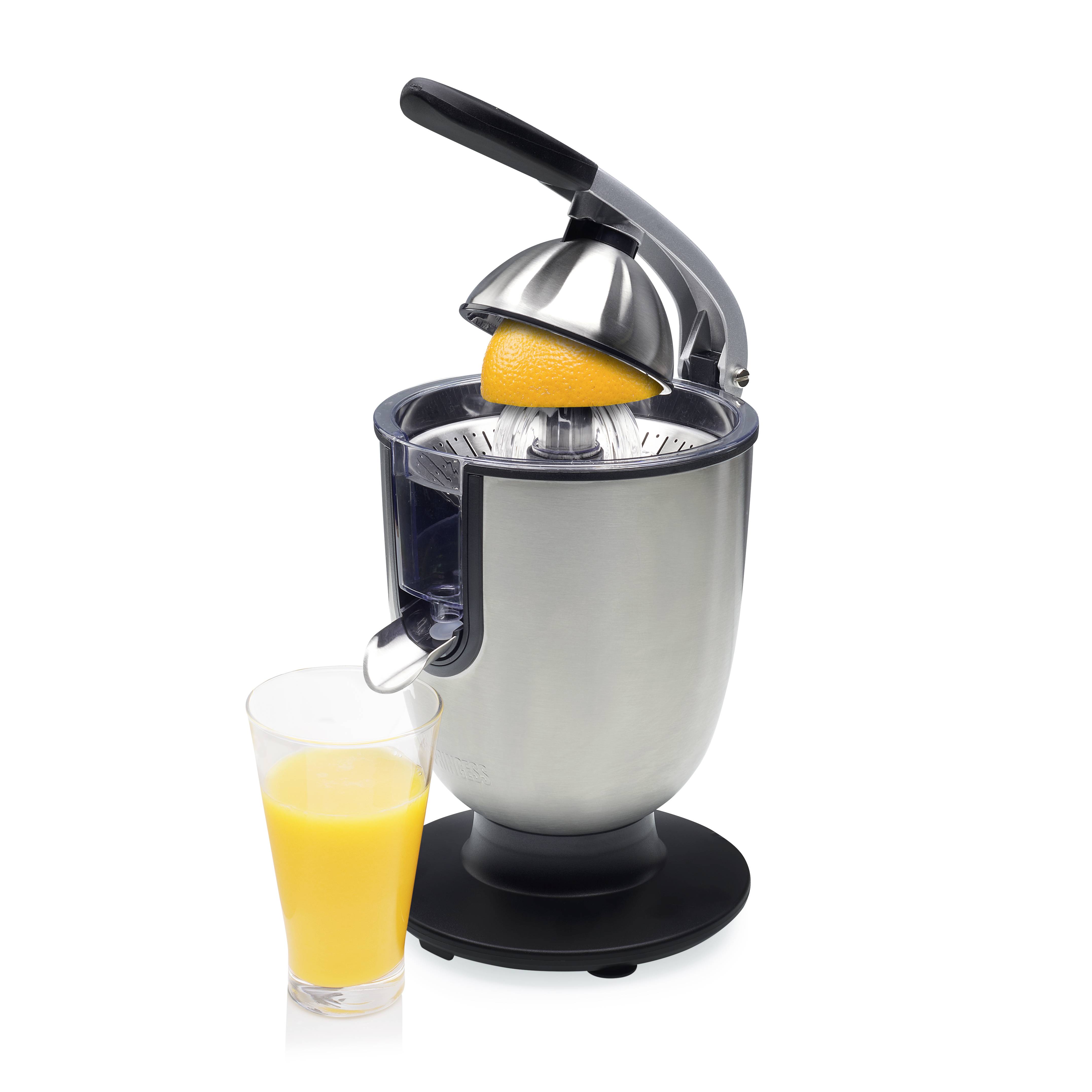Presse-agrumes manuel en argent avec un demi-orange dans le mécanisme de pressage, à côté d'un verre de jus d'orange fraîchement pressé.