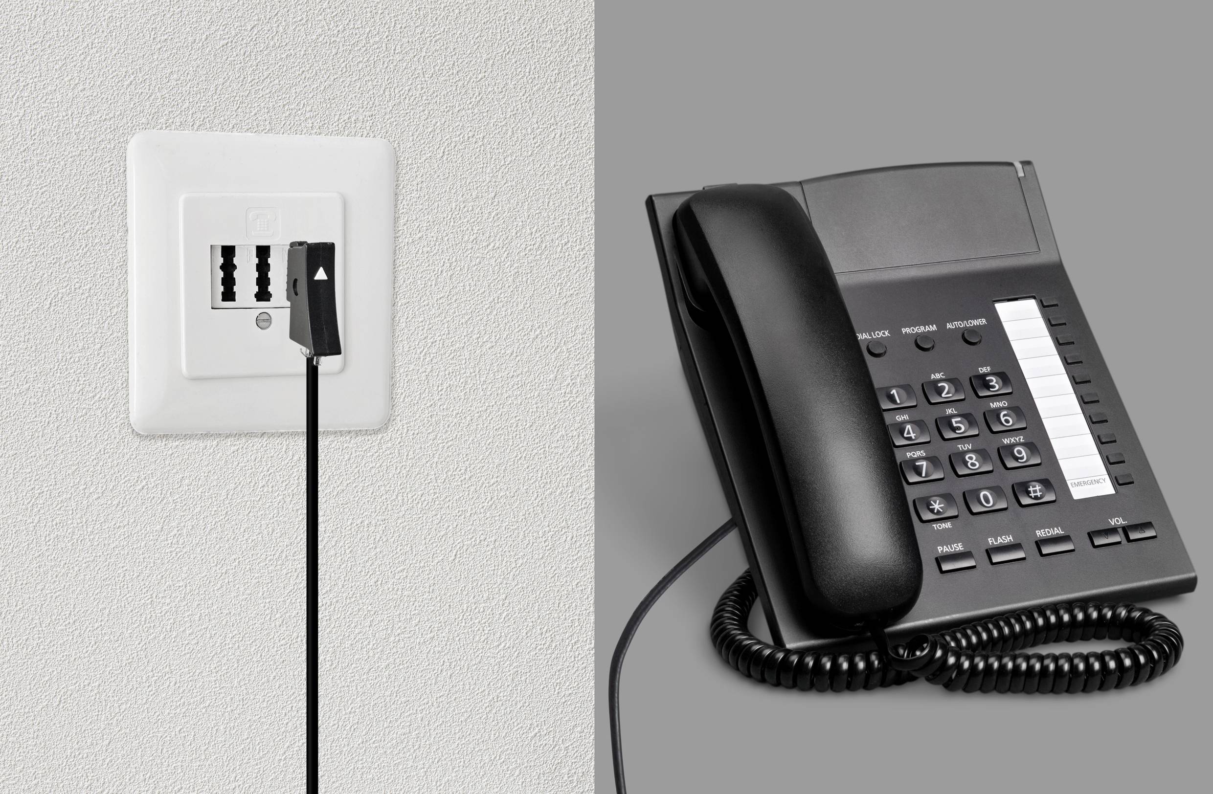 Un câble noir est connecté à une prise téléphonique, à côté d'un téléphone de bureau sur un fond gris.