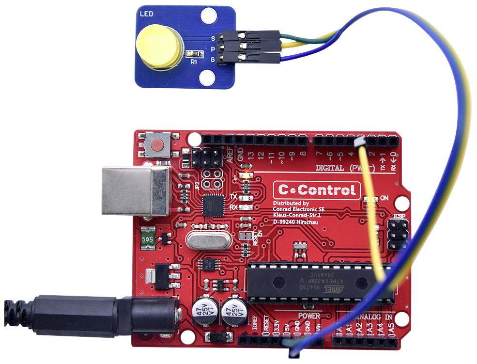 Carte de microcontrôleur rouge avec port USB et module de capteur à LED bleue, connectés par des câbles, montrant un circuit électronique.