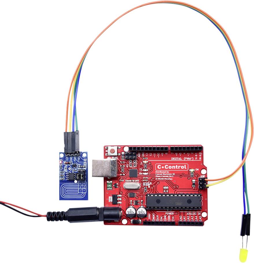 Une carte de microcontrôleur rouge avec un composant capteur bleu connecté et des câbles.