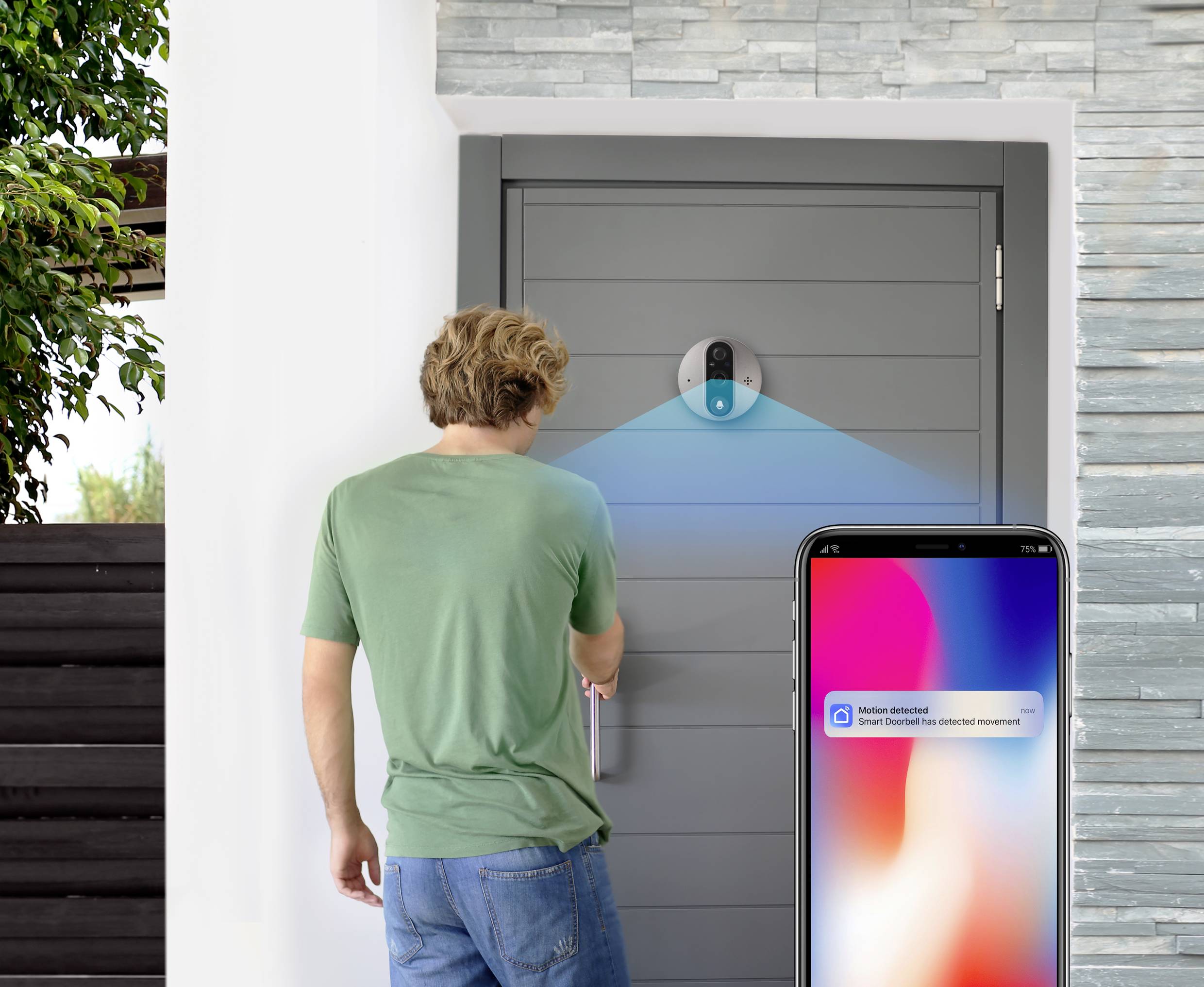 Un homme ouvre une porte avec une serrure connectée. Une notification sur son téléphone indique « Mouvement détecté ».