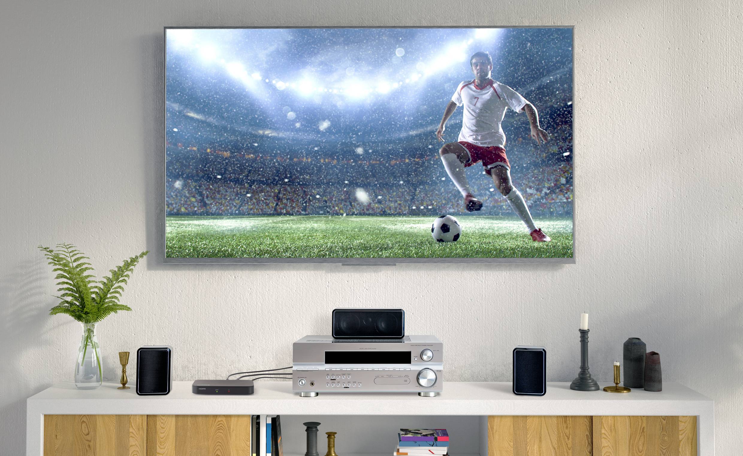 Un salon avec un téléviseur diffusant un match de football. Un joueur en short rouge conduit le ballon dans un stade illuminé.