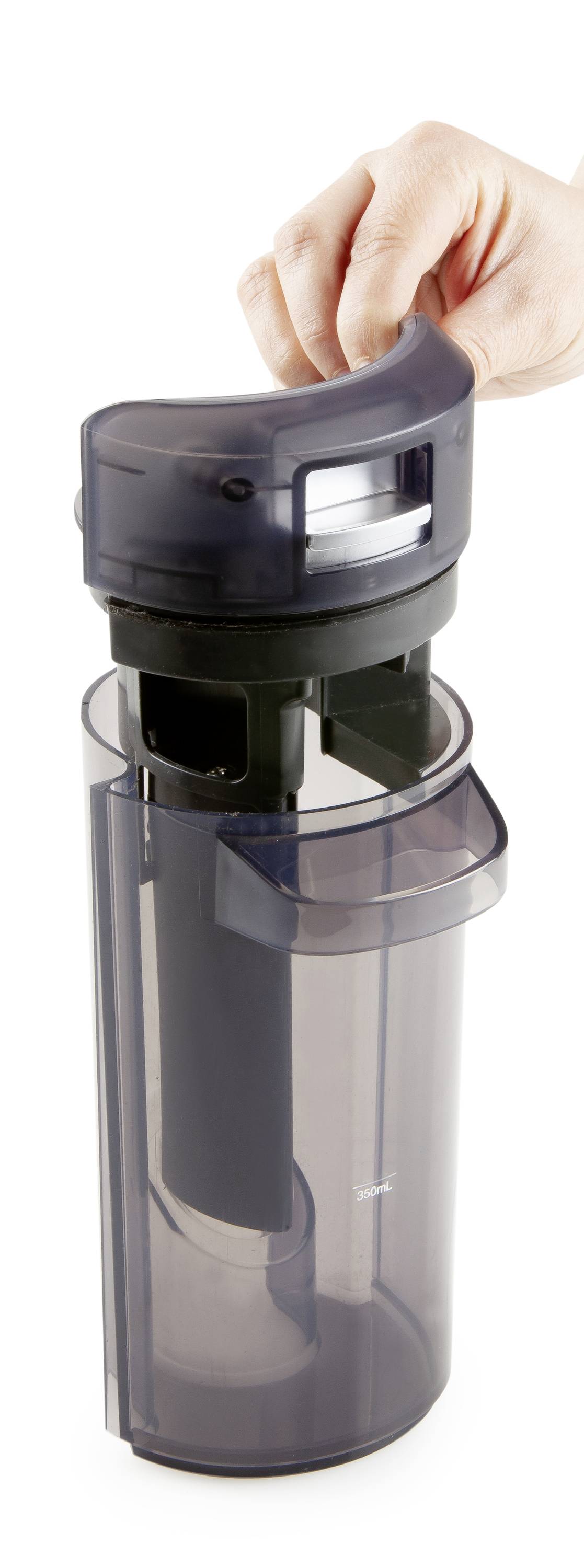 Une main ouvre le couvercle d'un récipient cylindrique transparent à charnière. Le récipient semble moderne et fonctionnel.