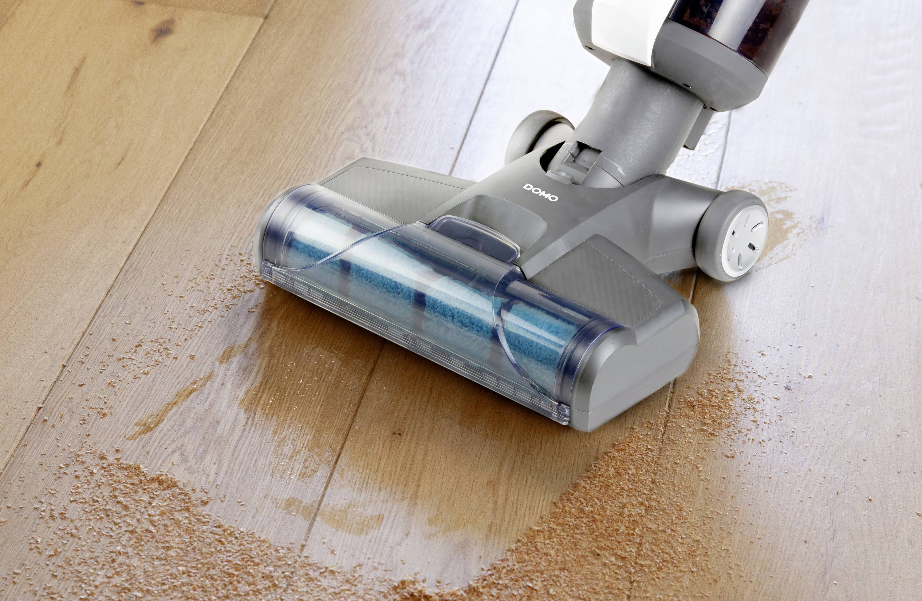 Un aspirateur enlève des miettes d'un plancher en bois et démontre ses performances de nettoyage.