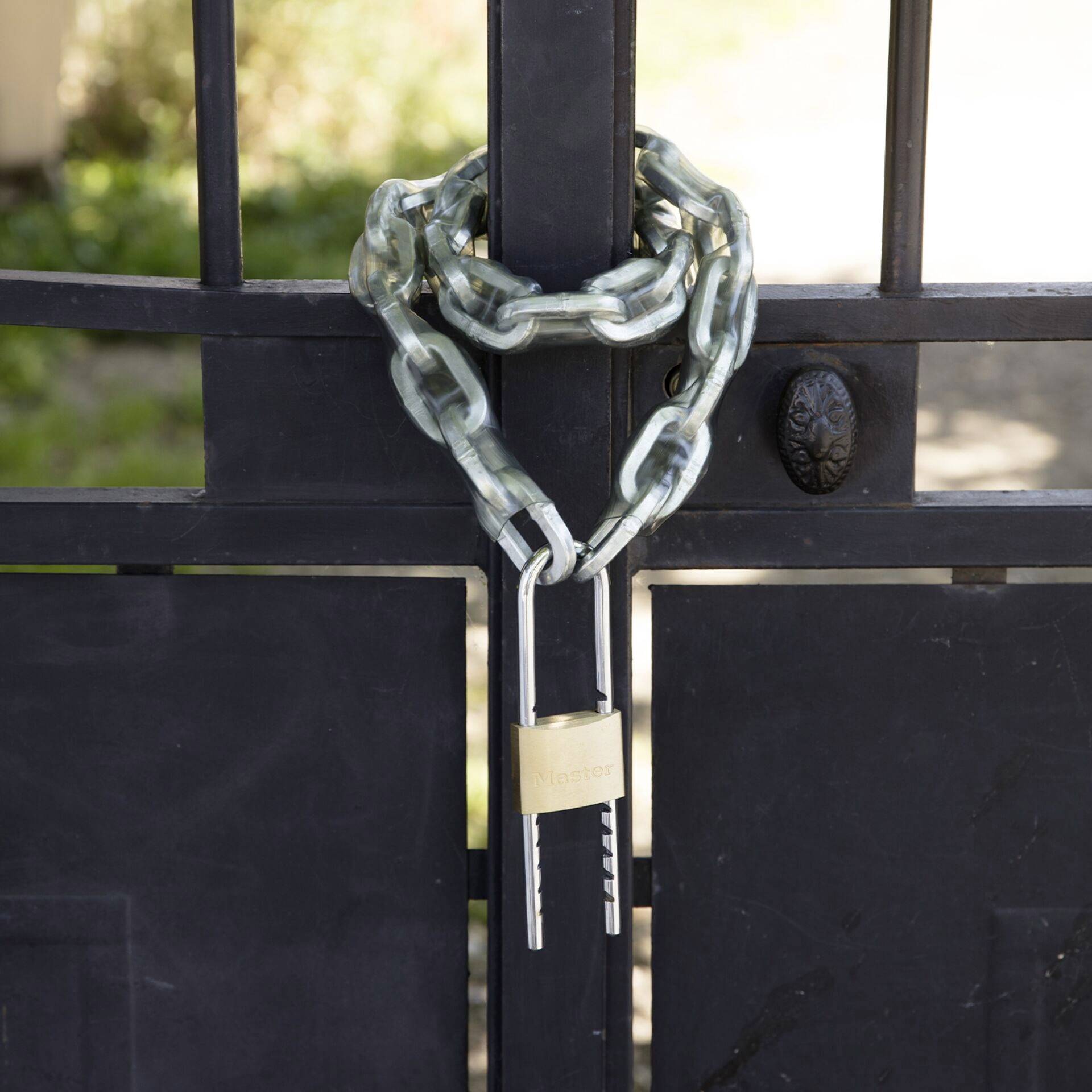 Une grille noire est sécurisée par une lourde chaîne métallique et un cadenas, ce qui suggère une limitation ou une protection.