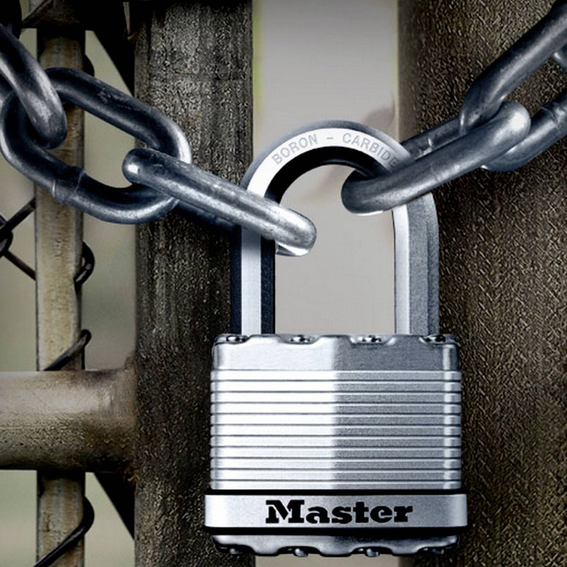 Un cadenas argenté portant l'inscription 'Master' sécurise une chaîne métallique sur une clôture.