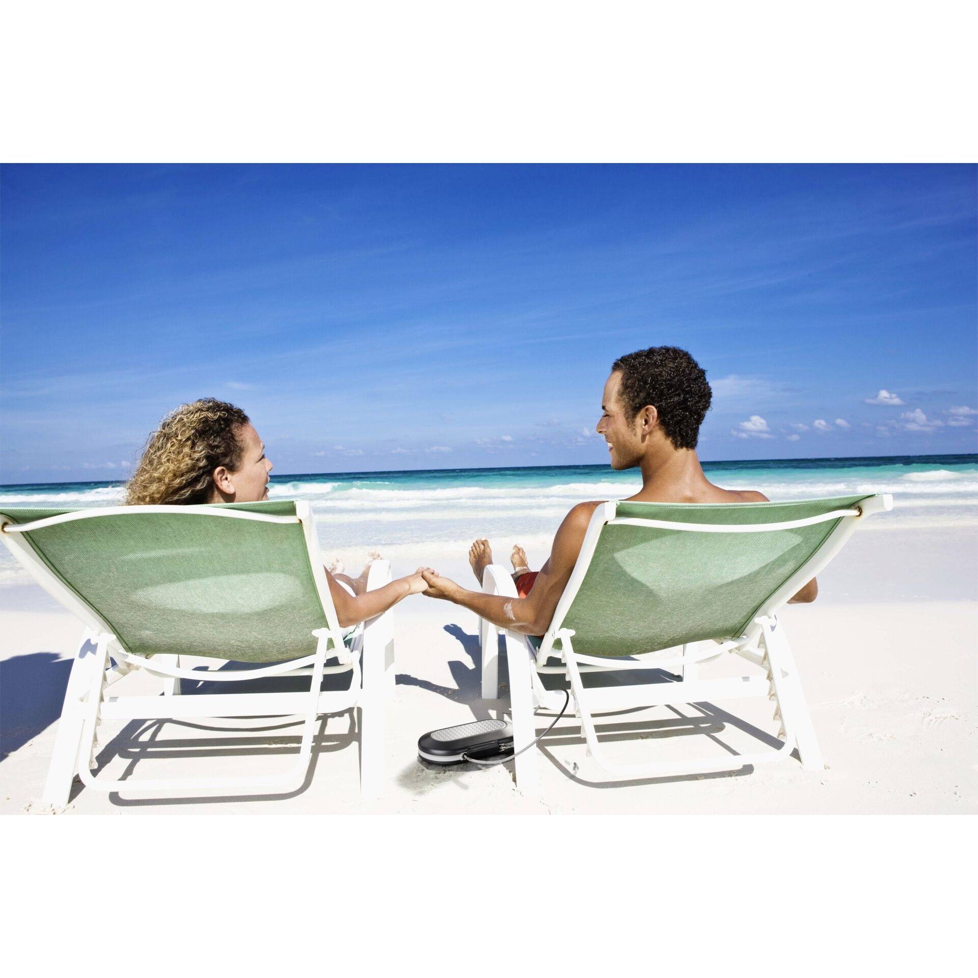 Un couple est assis de manière détendue sur des transats sur la plage, se tenant la main et regardant la mer par une journée ensoleillée.