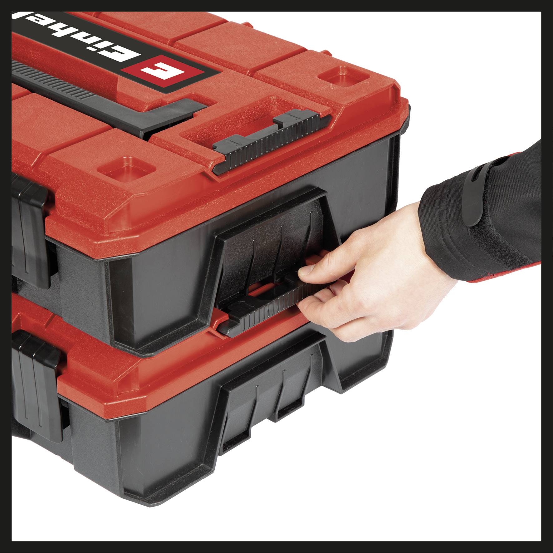 Une main tire sur la poignée d'un coffret à outils empilé de couleur rouge.