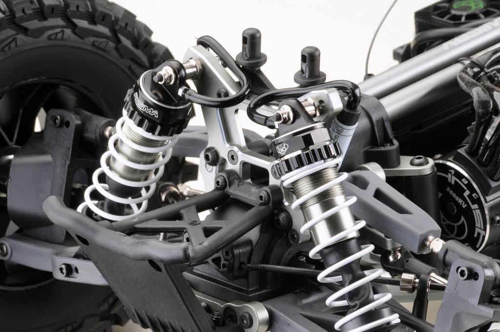 Gros plan sur le châssis d'une voiture miniature avec suspension et amortisseurs. On peut y voir la suspension de roue, les ressorts et différents détails techniques.