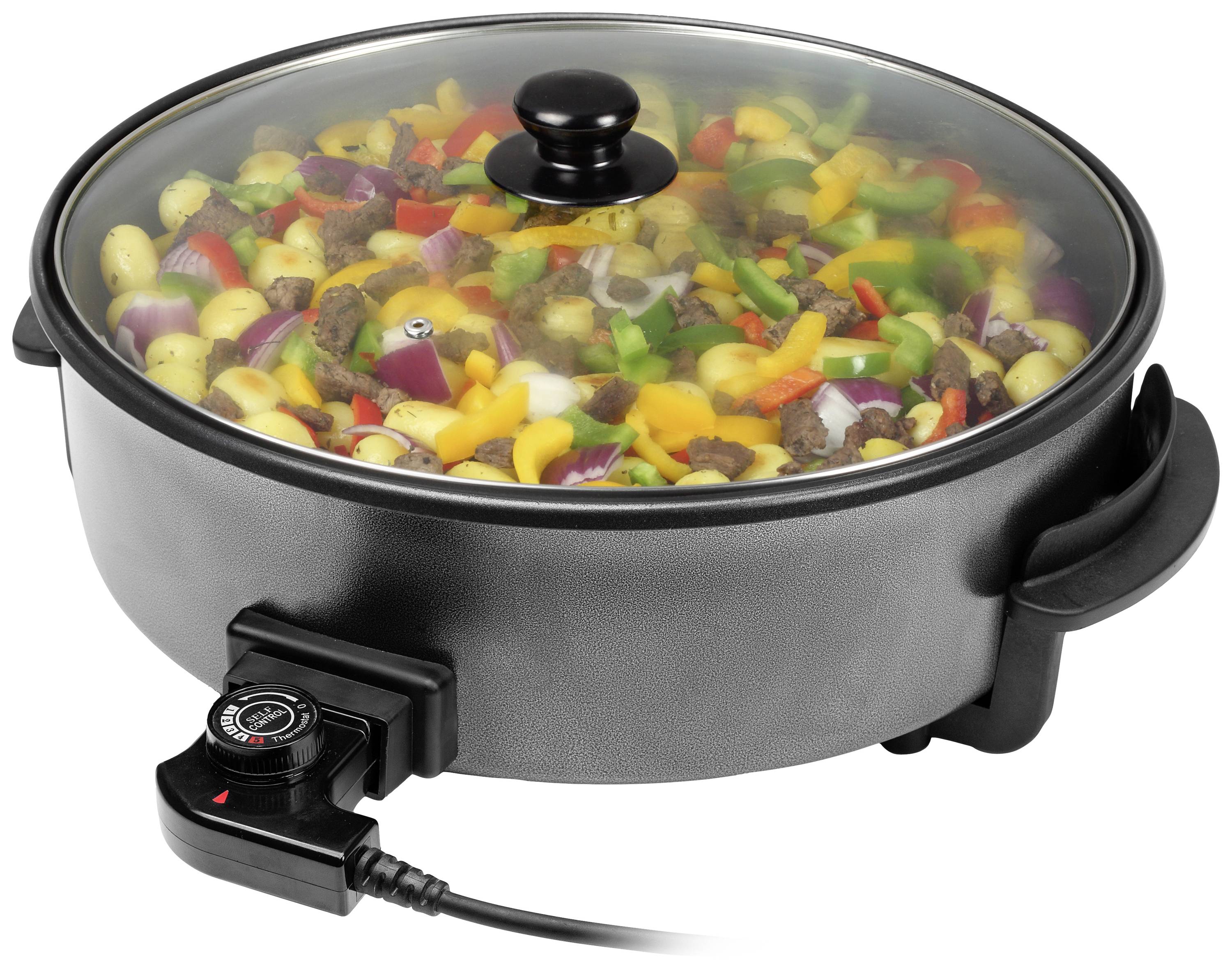 Poêle électrique avec des légumes et des morceaux de viande sous un couvercle en verre, régulateur de température branché sur le côté.