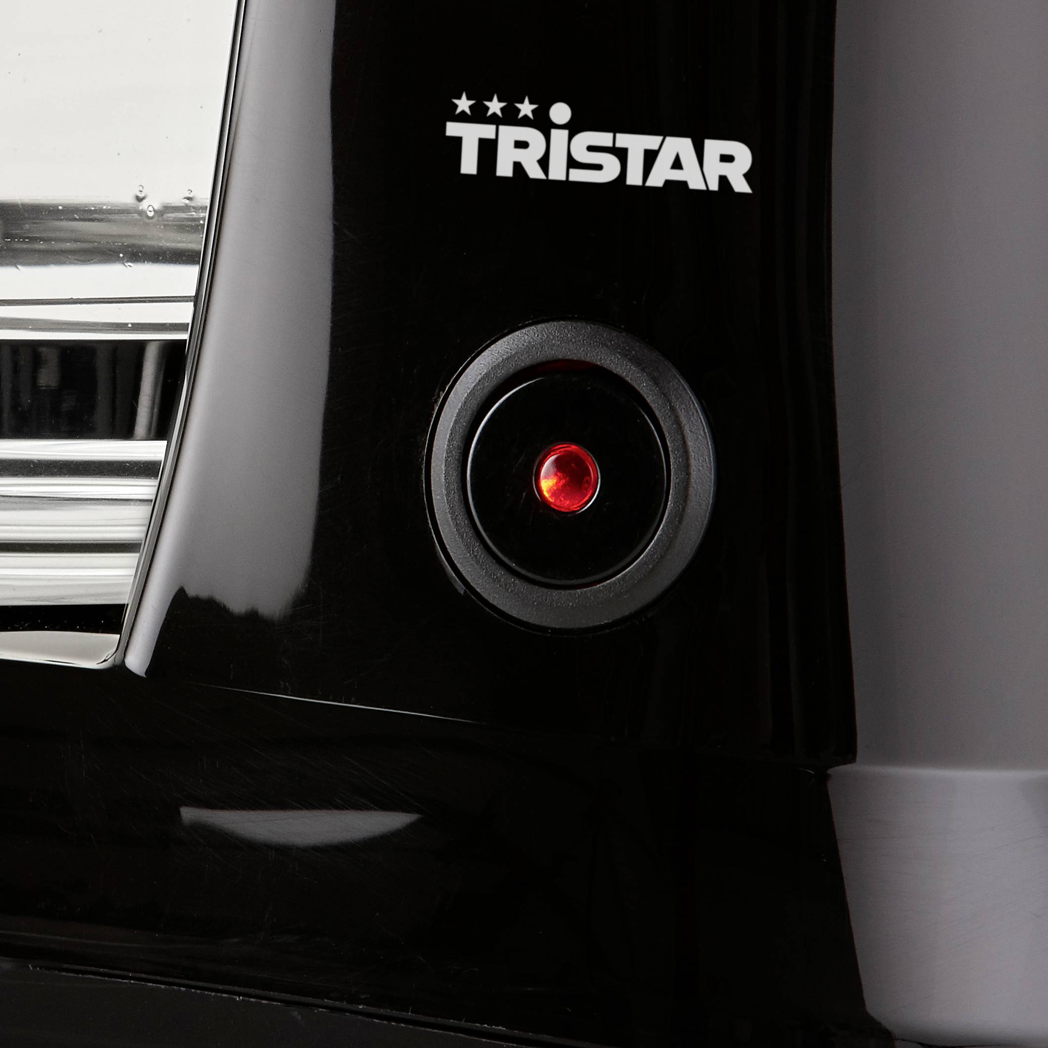 Gros plan d'un appareil noir avec un bouton rouge lumineux portant l'inscription 'Tristar'.