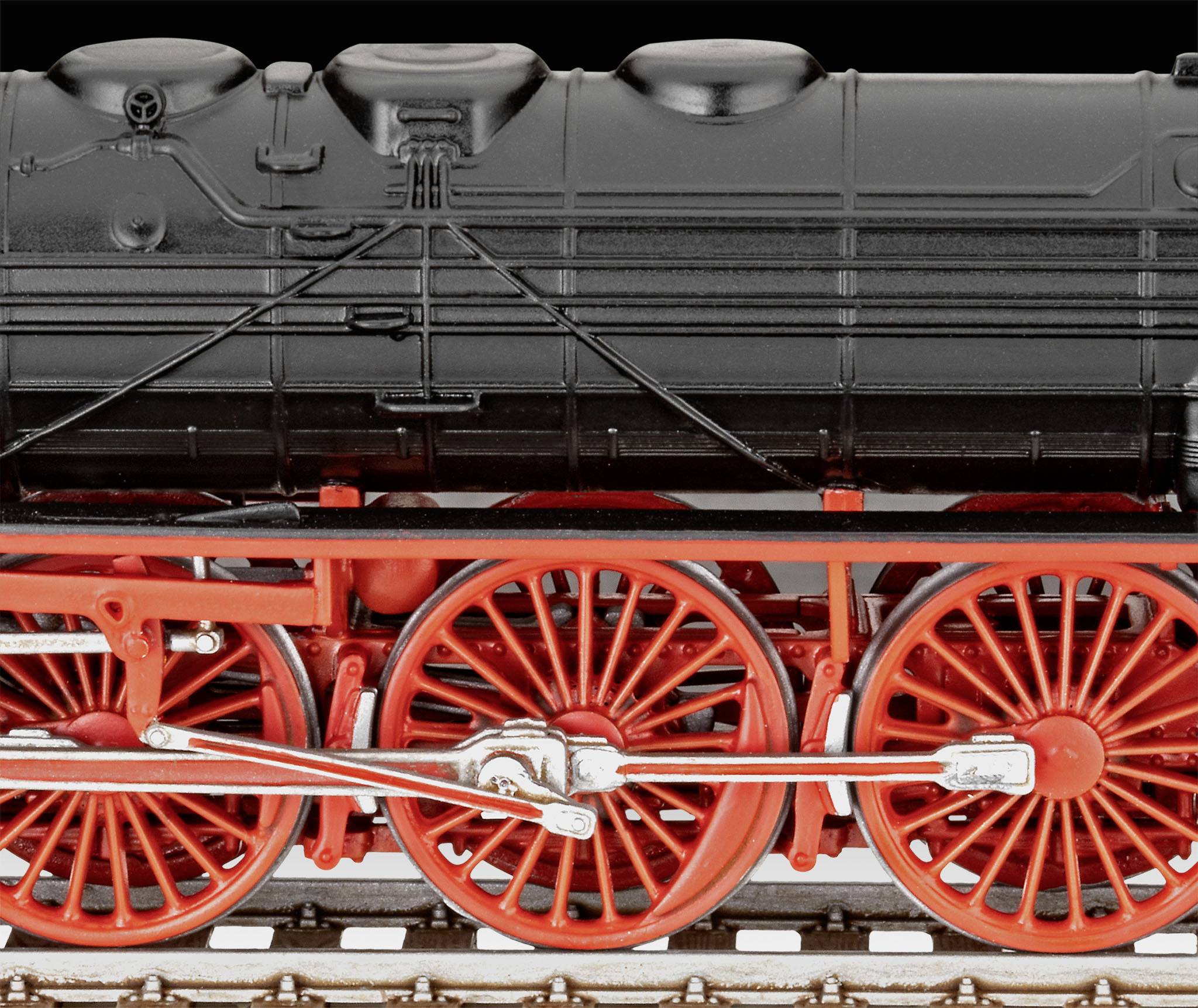 Gros plan d'une chaudière de locomotive à vapeur noire avec des roues rouges et des rails argentés, sur un fond sombre.