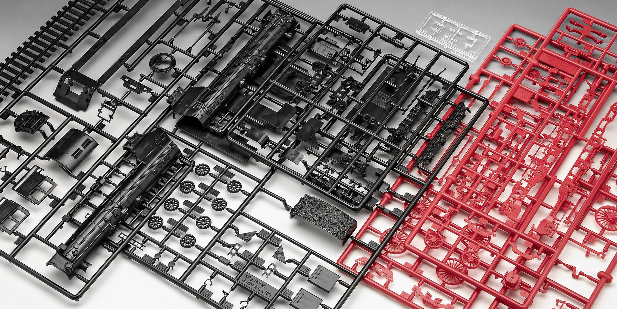 Kit de construction en plastique pour modèles réduits de trains avec des châssis en treillis noirs et rouges, contenant des pièces individuelles pour locomotives.