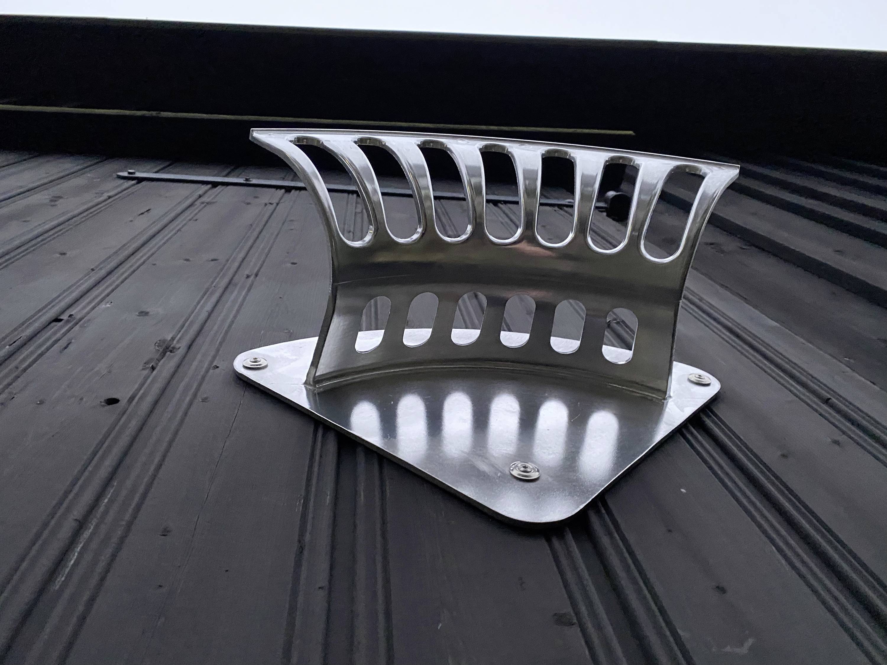 Une grille de protection contre les chutes de neige en argent sur un toit métallique sombre. Elle est de forme trapézoïdale et fixée avec des vis pour retenir la neige.