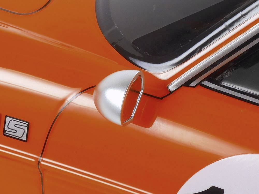 Gros plan sur une voiture vintage orange. On peut voir une partie de la portière côté conducteur avec un rétroviseur latéral argenté.