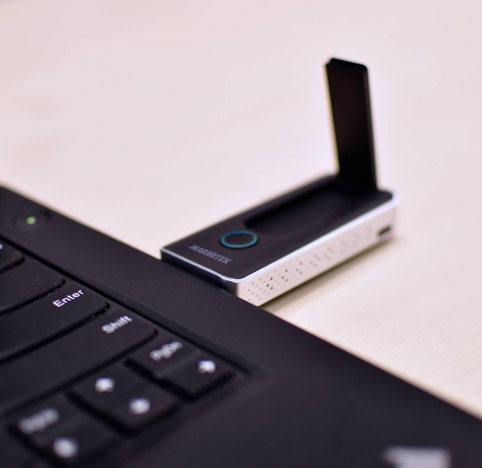 Une clé USB est branchée dans un ordinateur portable. La clé est noir et blanc avec une inscription sur le devant.