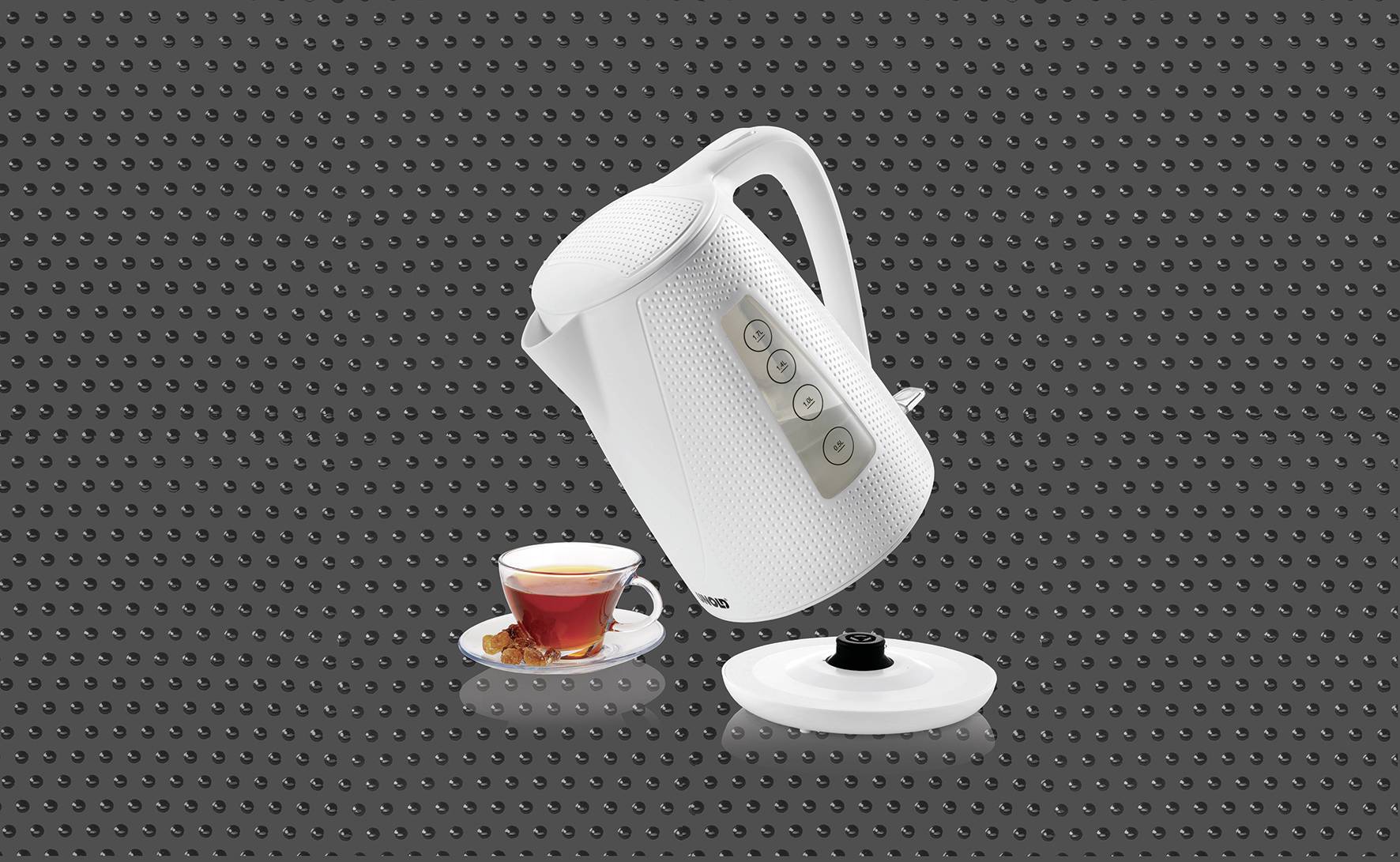 Un bouilloire blanche verse un liquide dans une tasse de thé posée sur une soucoupe, devant un fond à pois.