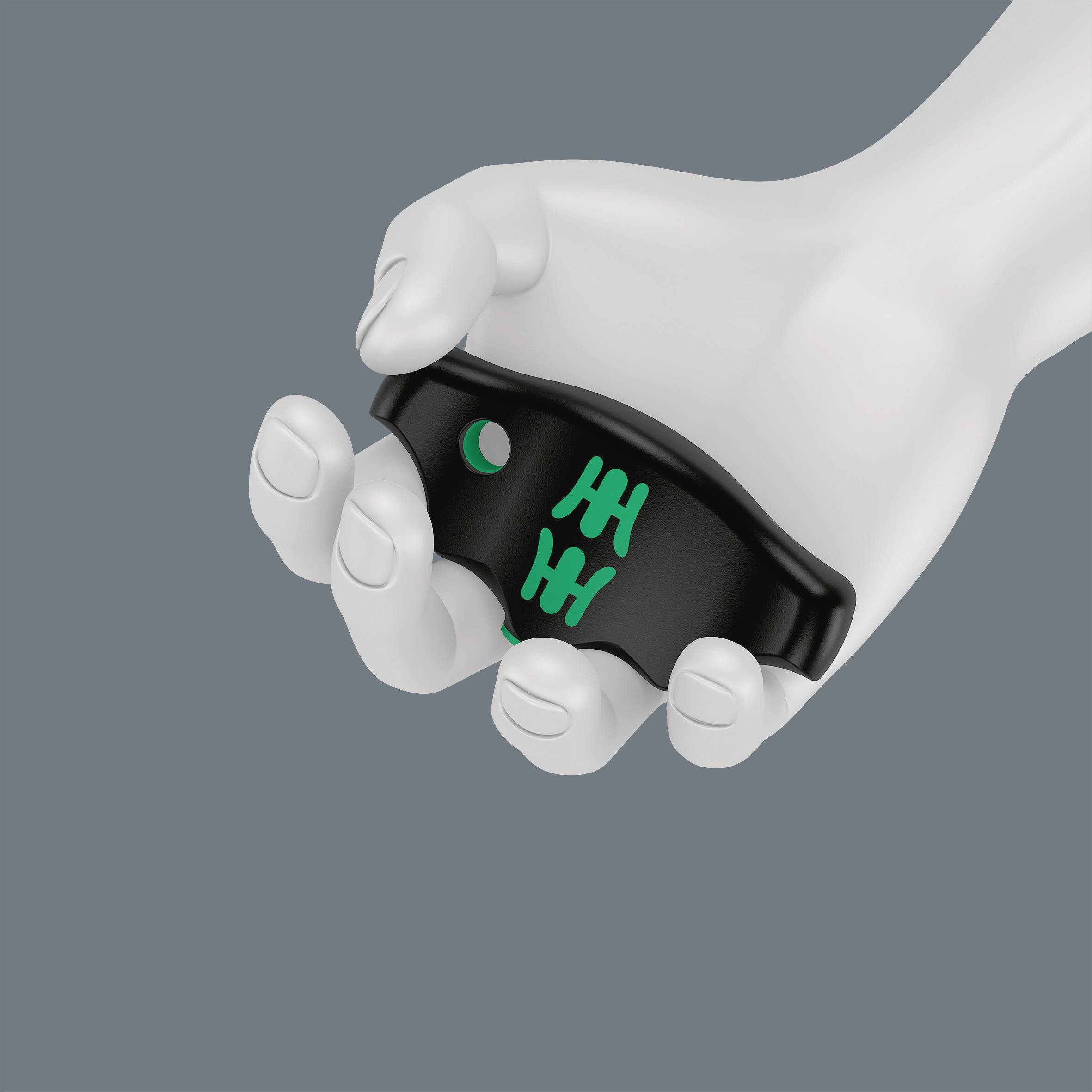 Une main blanche tient une manette de jeu noire avec des touches vertes devant un fond gris.