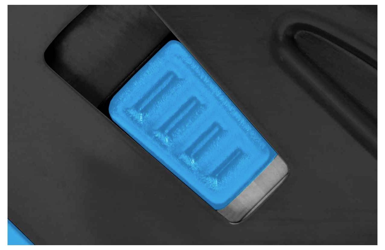 Gros plan d'un interrupteur bleu rectangulaire sur une surface noire, probablement un composant d'un appareil électronique.