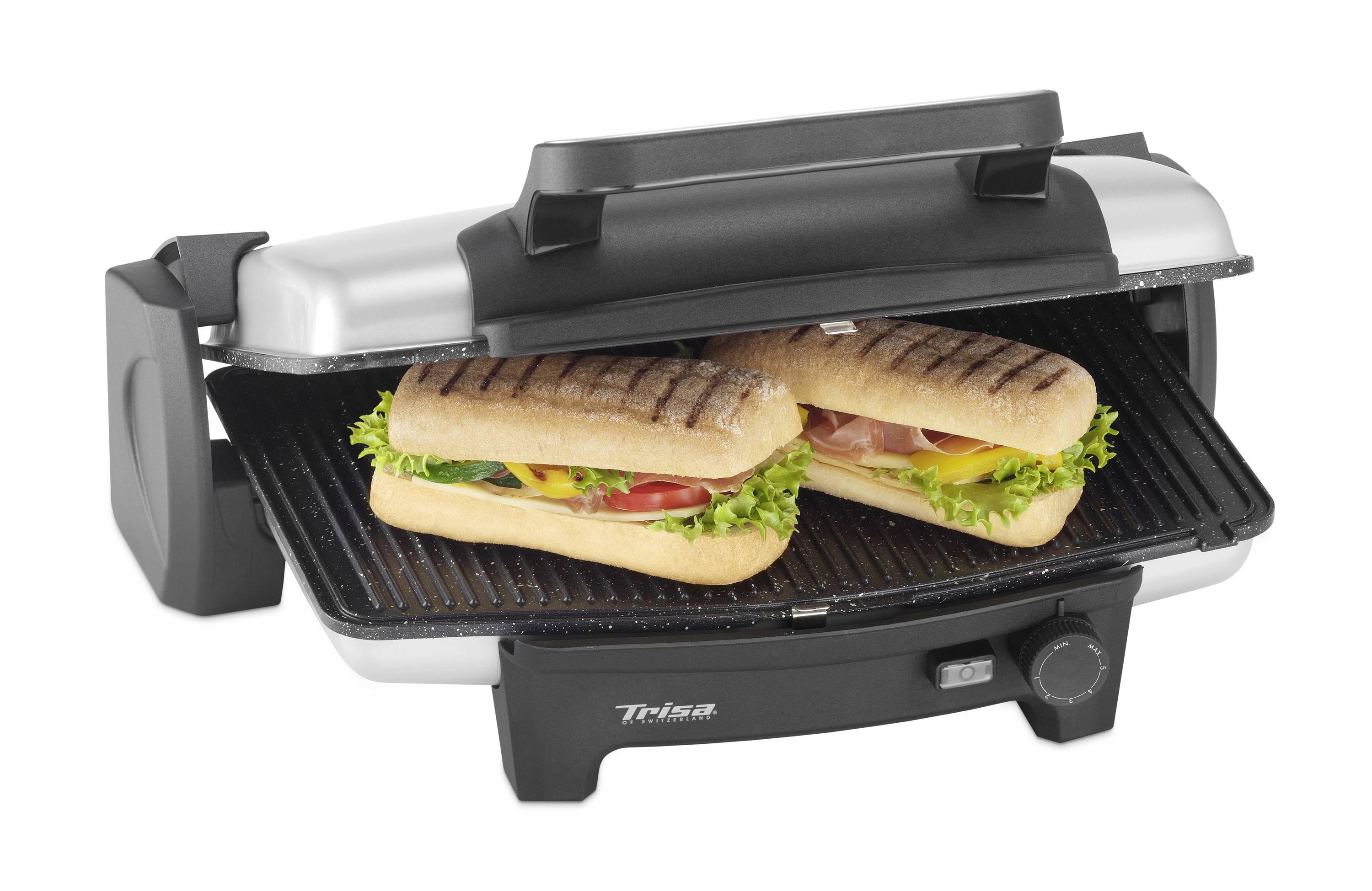 Un grill électrique à contact avec deux sandwichs panini grillés, garnis de salade, tomate et jambon.