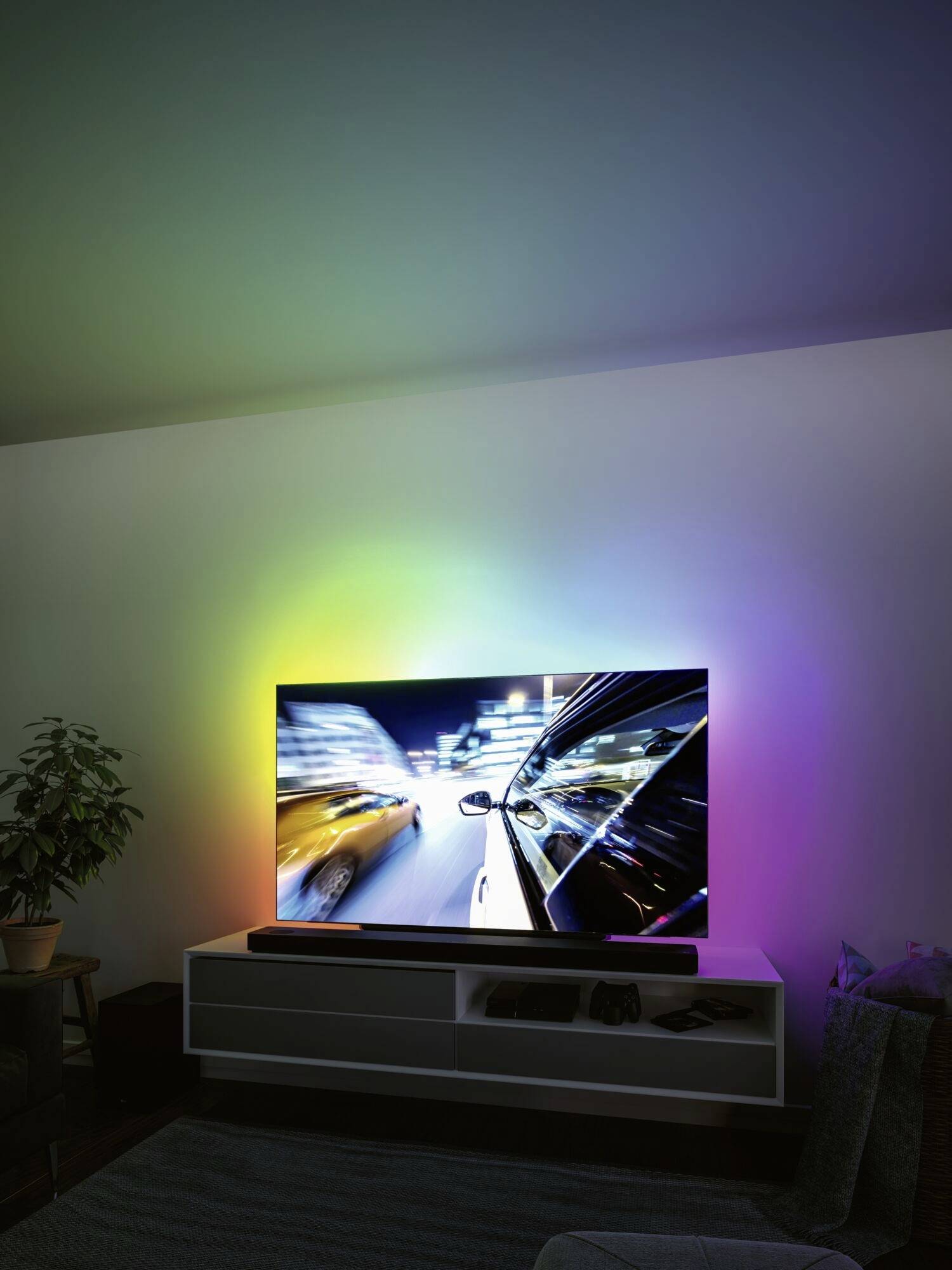 Un téléviseur avec un éclairage de fond coloré affiche une scène floue de voitures en mouvement.