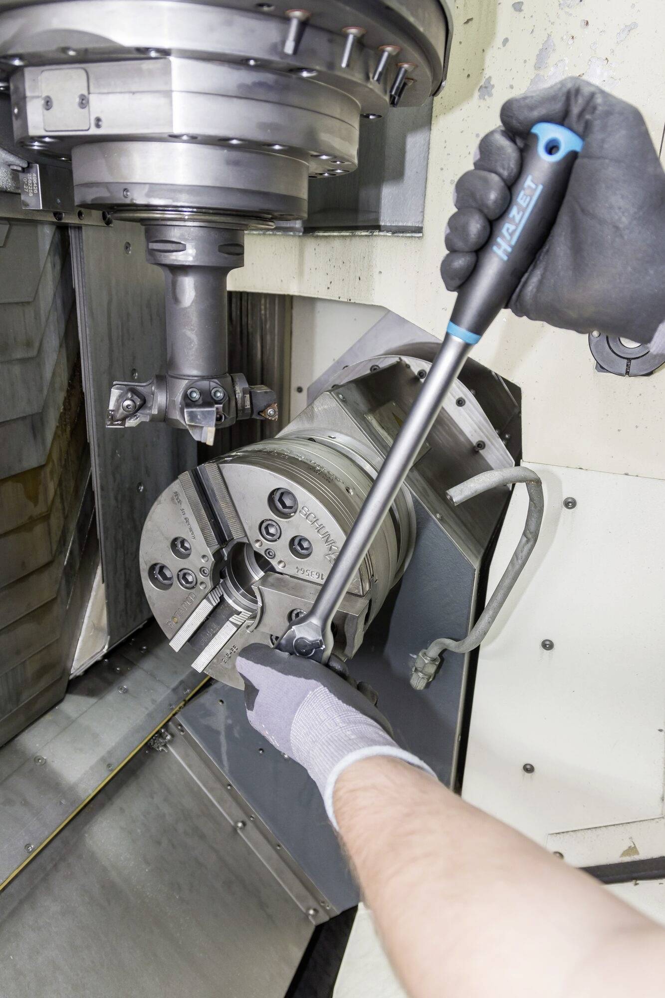 Une personne fixe une pièce dans une machine CNC à l'aide d'une clé dynamométrique, probablement dans un environnement industriel.