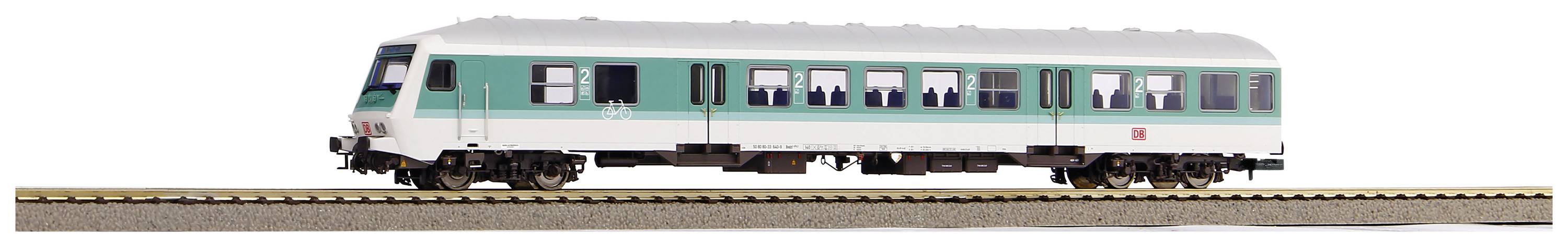 Une voiture de voyageurs turquoise et blanche sur une voie ferrée, avec des passagers visibles à travers les fenêtres.