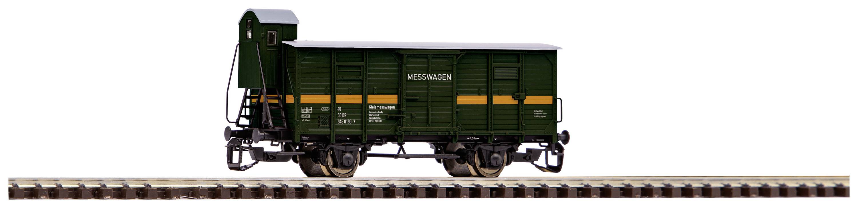 Un wagon de marchandises vert est stationné sur un tronçon de voie ferrée. Le wagon porte l'inscription 'WSTBAHNEN'.