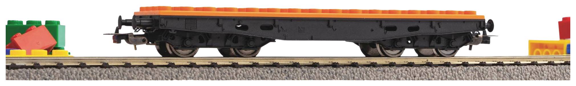 Un wagon de chemin de fer en briques Lego noires avec un bord supérieur orange est posé sur une voie ferrée, entouré de blocs de construction colorés.