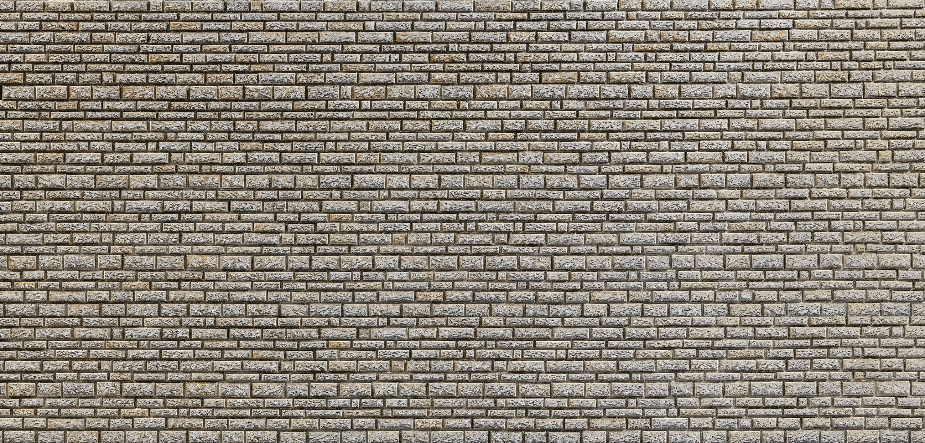Un mur uniforme en briques jaunâtres, formant une structure stable et solide.