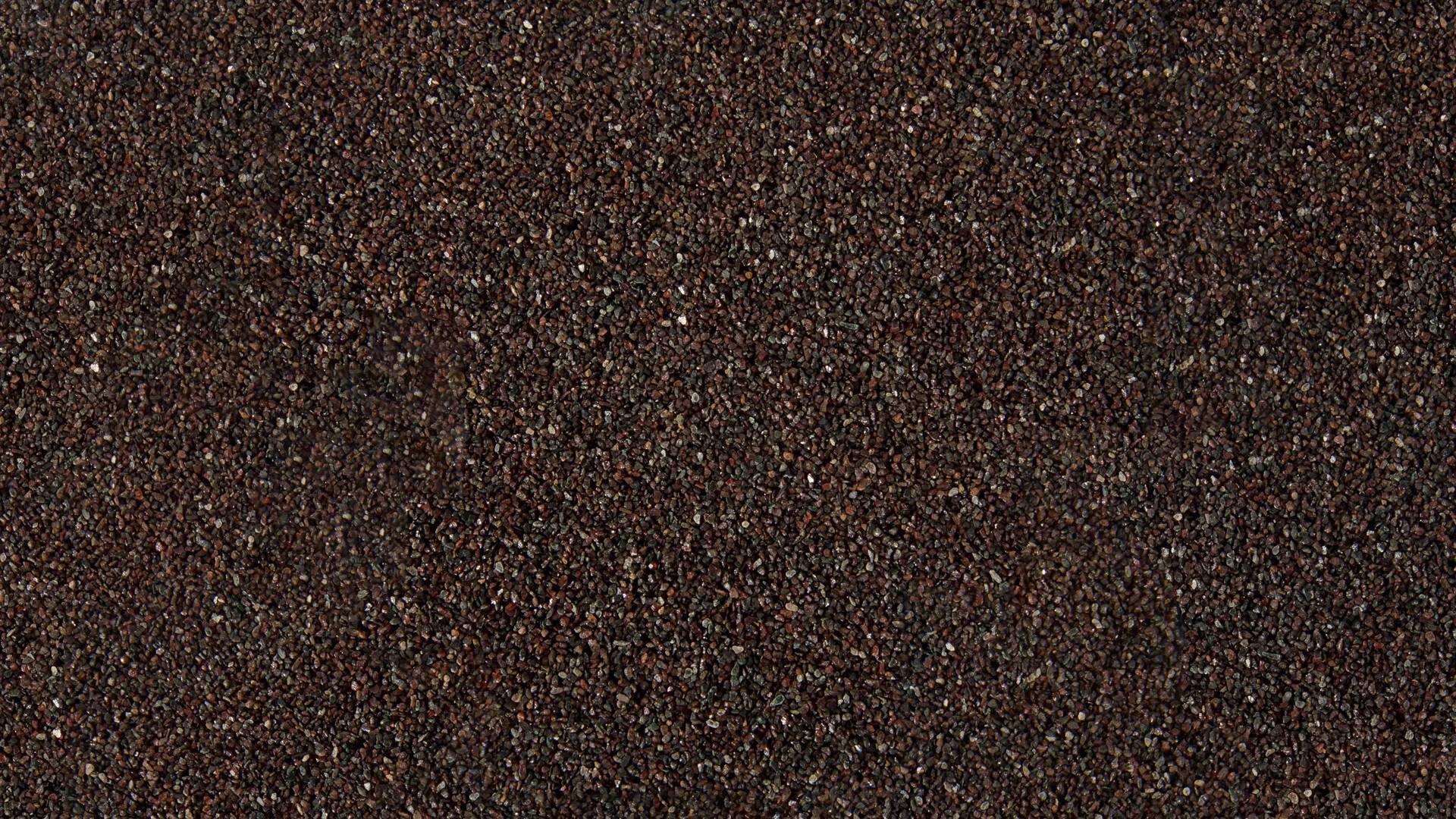 Gros plan sur du papier de verre brun granuleux, présentant une texture rugueuse.