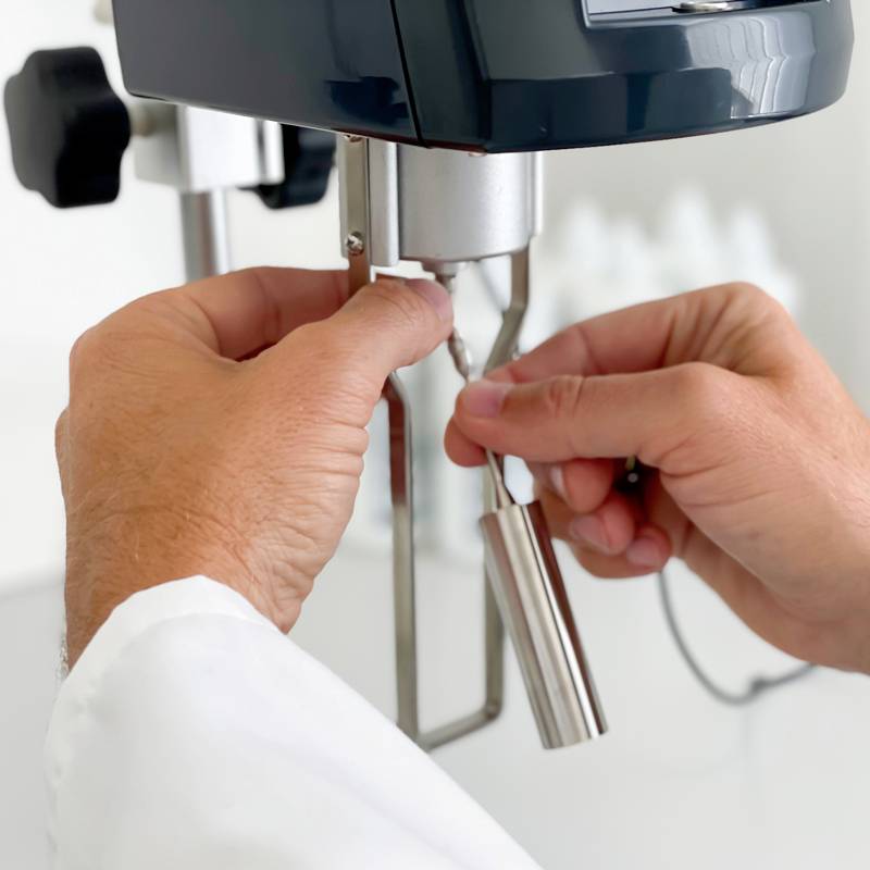 Une personne actionne une machine à espresso et tient le porte-filtre. Les mains sont visibles dans une pièce claire et propre.