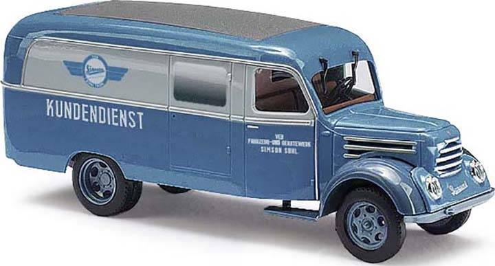 Camionnette de service rétro bleu et blanc avec l'inscription 'SERVICE CLIENT' sur le côté. Le véhicule présente des marquages et un design nostalgique.