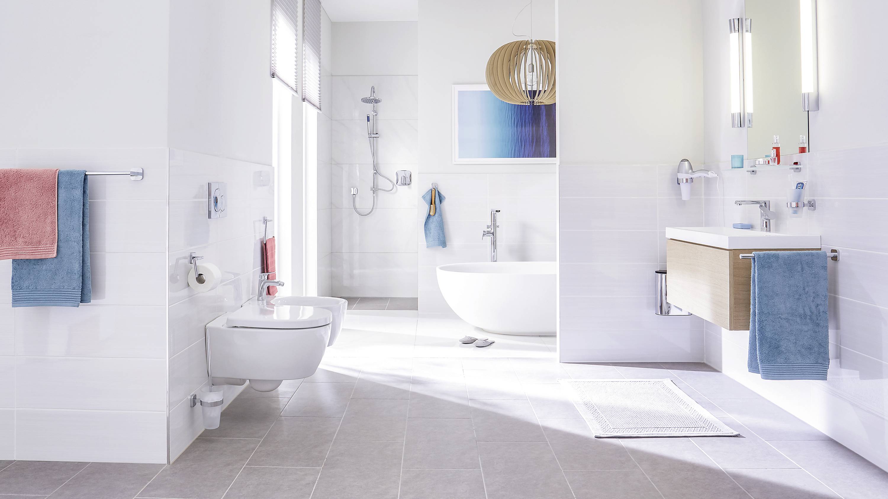 Salle de bain spacieuse et moderne avec baignoire îlot, lavabo, douche et serviettes de différentes couleurs.