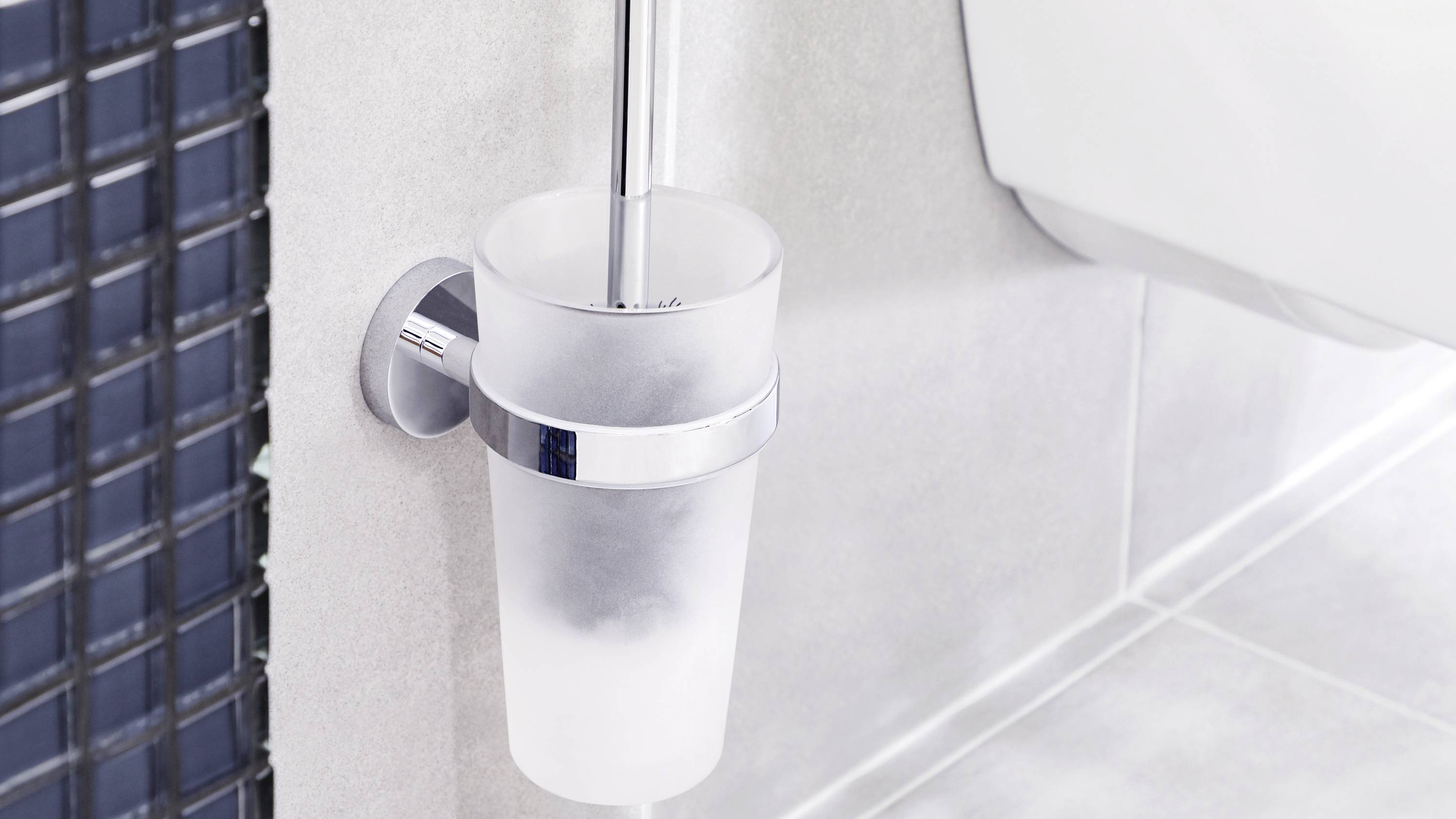 Brosse de toilettes dans son support fixé au mur, faisant partie d'une salle de bain moderne.