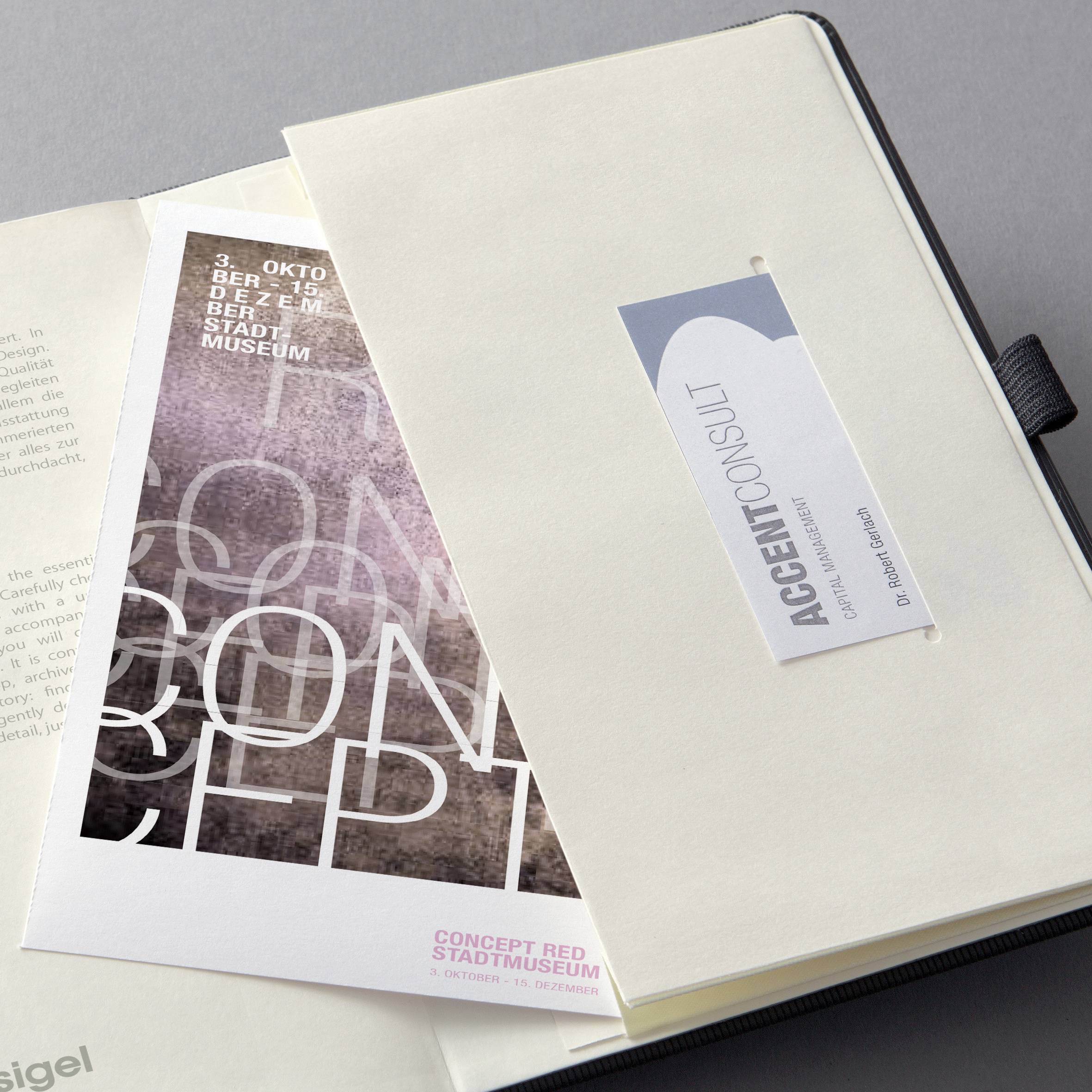 Un dossier avec un dépliant pour l'exposition 'CONCEPT' au musée municipal, visible à côté d'une carte de visite de ACCENT consult.
