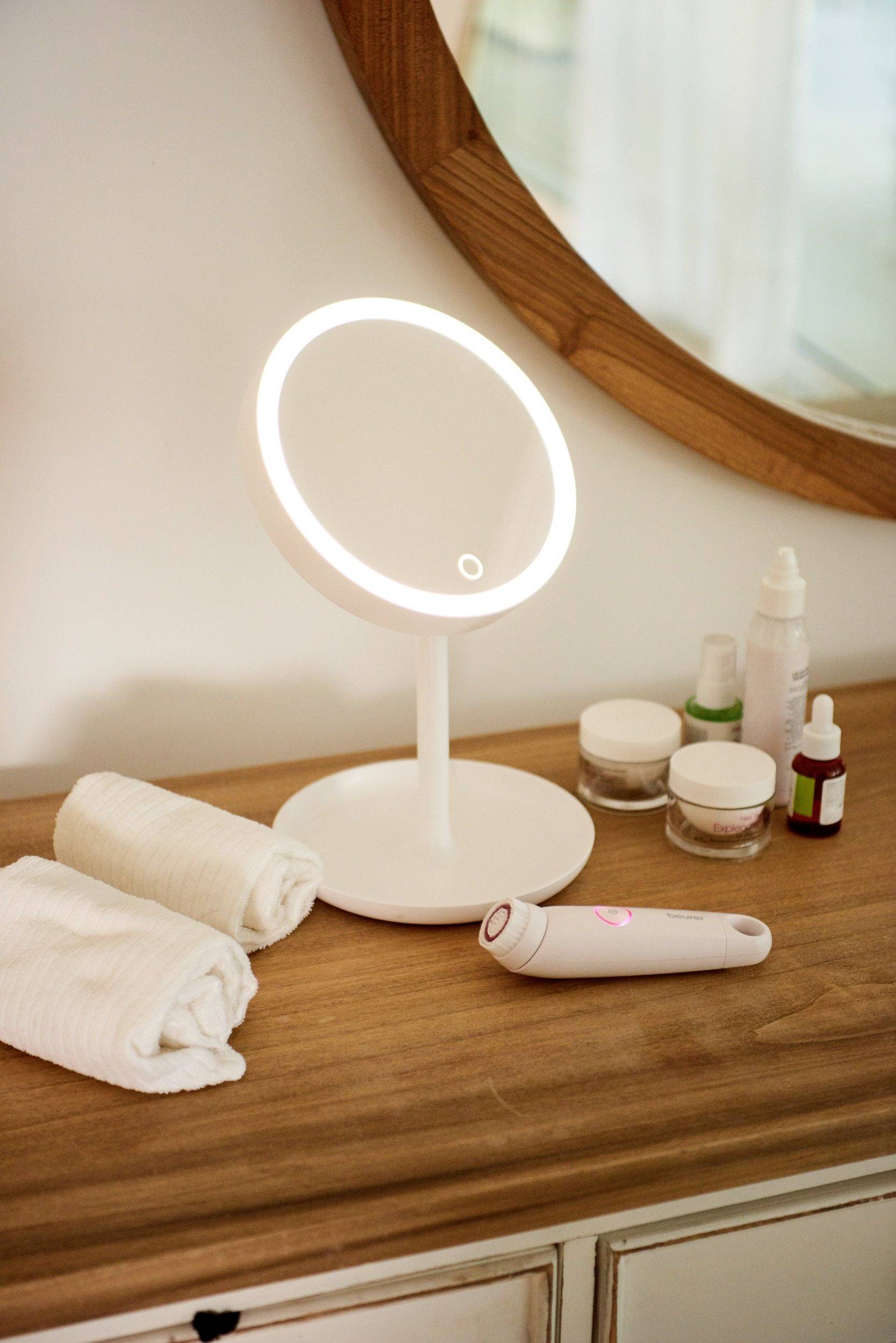 Table de toilette avec miroir de maquillage éclairé, serviettes et produits de soin.
