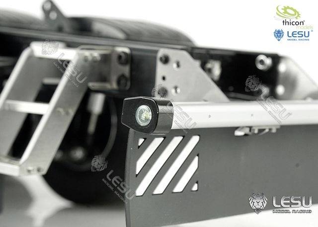 Gros plan d'un châssis de camion de modélisme avec des pièces métalliques et un éclairage LED. Les logos de marque de 'thicon' et 'LESU' sont visibles.
