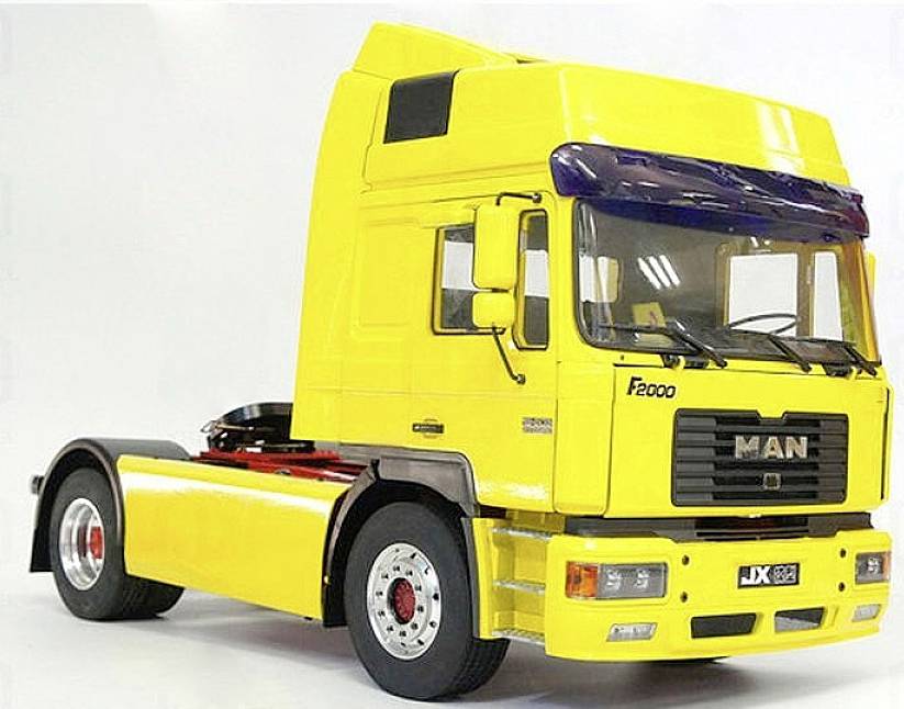 Un camion jaune de marque MAN F2000, sans remorque, est stationné sur le côté sur un fond blanc.