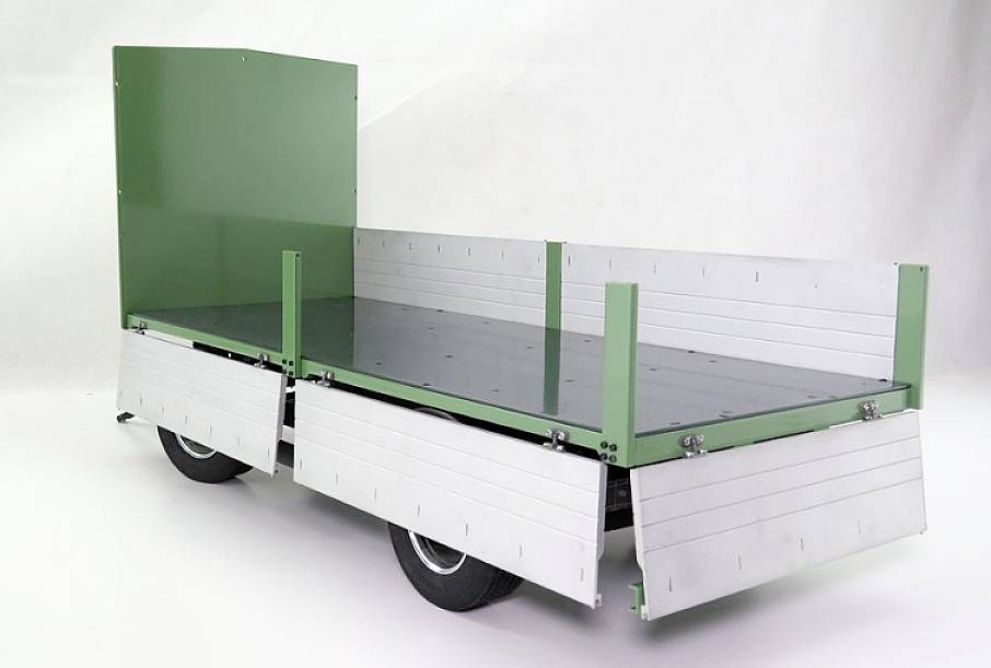 Remorque verte avec parois latérales en métal, montée sur roues, sur fond blanc, adaptée au transport de marchandises ou de matériaux.