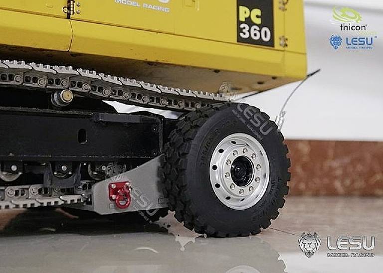 Modèle réduit d'un camion jaune portant l'inscription 'PC 360'. Vue détaillée montrant la roue et le système de transmission à chaîne. La marque 'LESU' est visible sur la photo.