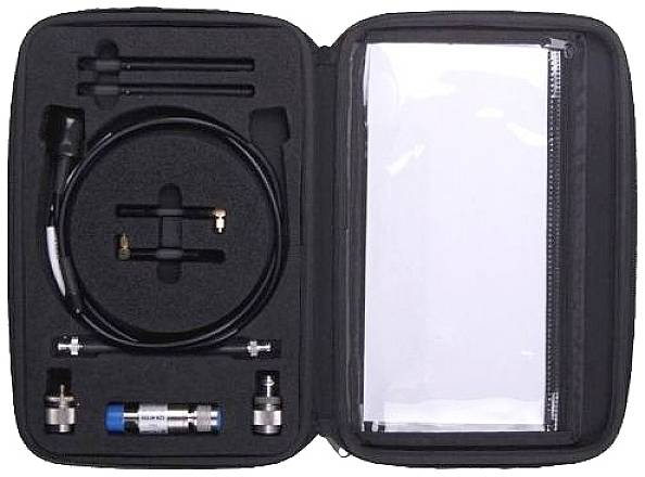 Un étui ouvert contenant divers appareils électroniques et câbles dans des compartiments bien rangés. À droite, un sac transparent.