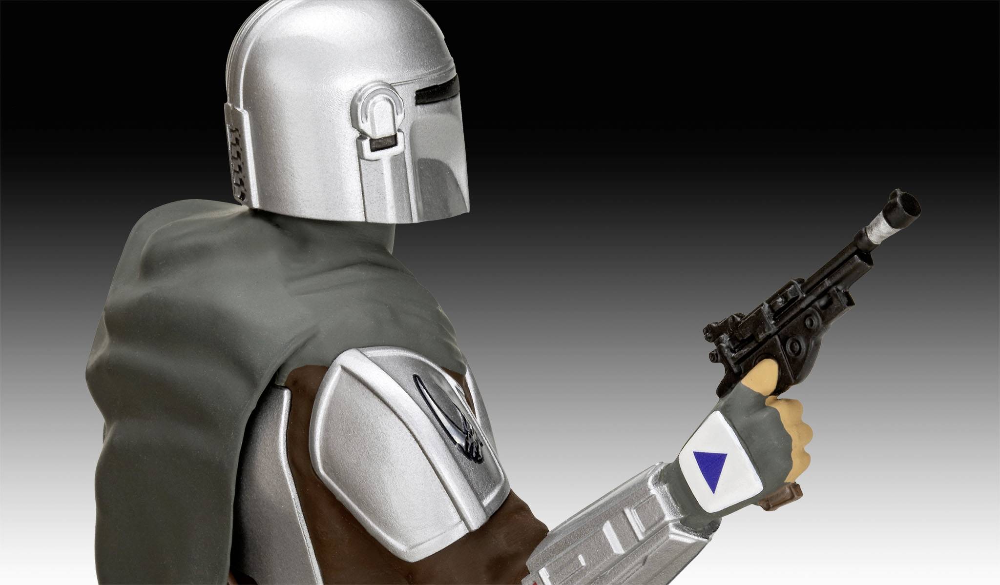 Une personne portant une armure argentée tient un pistolet. Elle porte une cape grise.