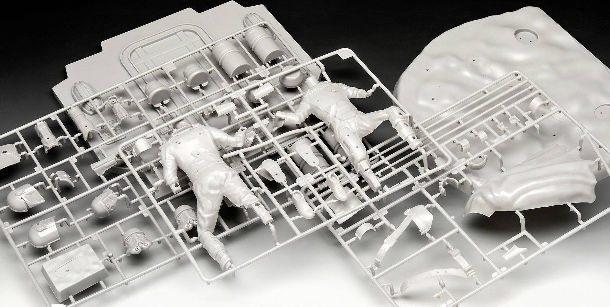 Plusieurs maquettes en plastique avec des pièces pour figurines, casques et outils sont étalées sur une surface.