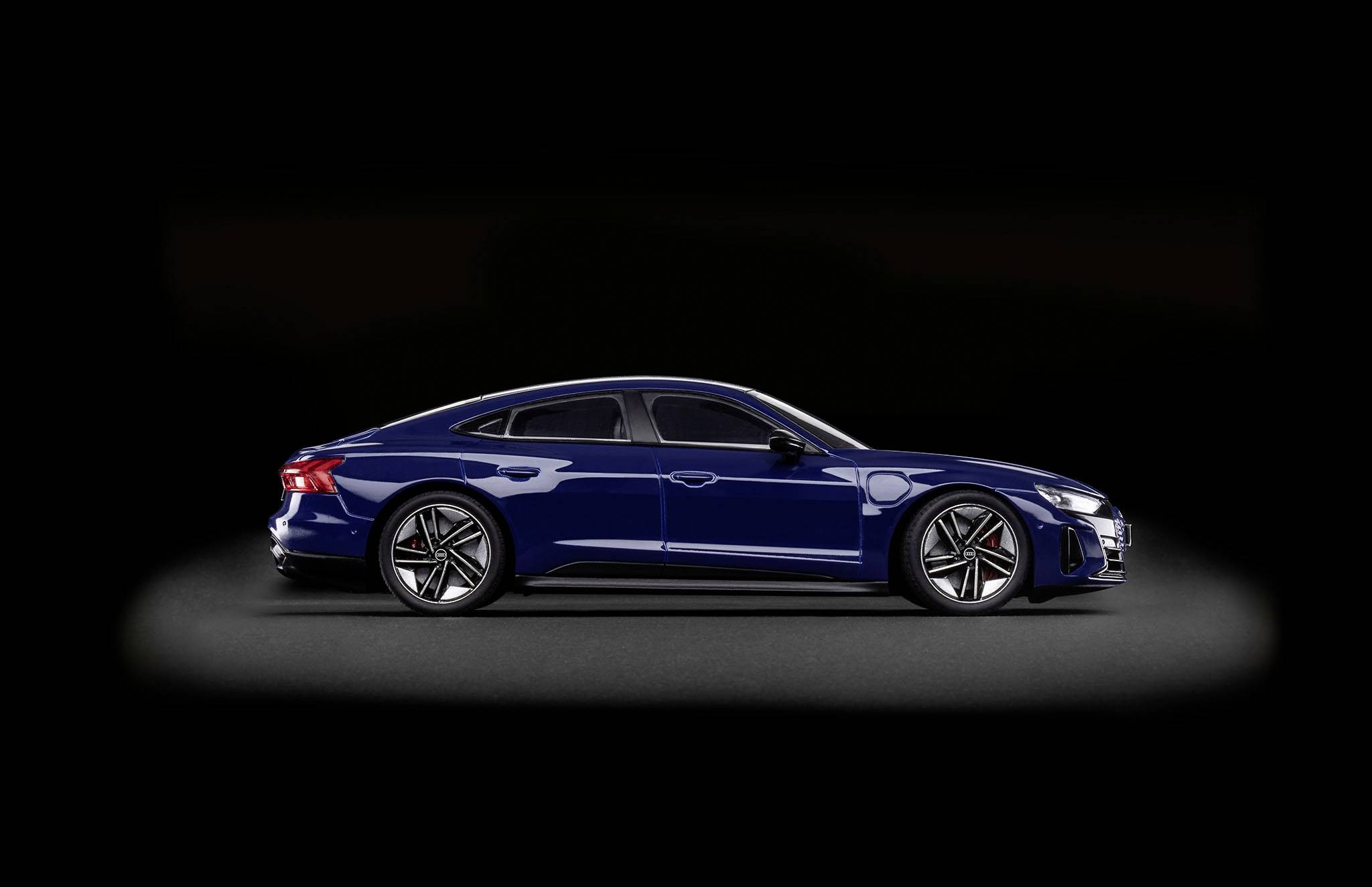 Voiture électrique bleue vue de côté sur un fond noir. Accent mis sur le design aérodynamique et les jantes modernes.