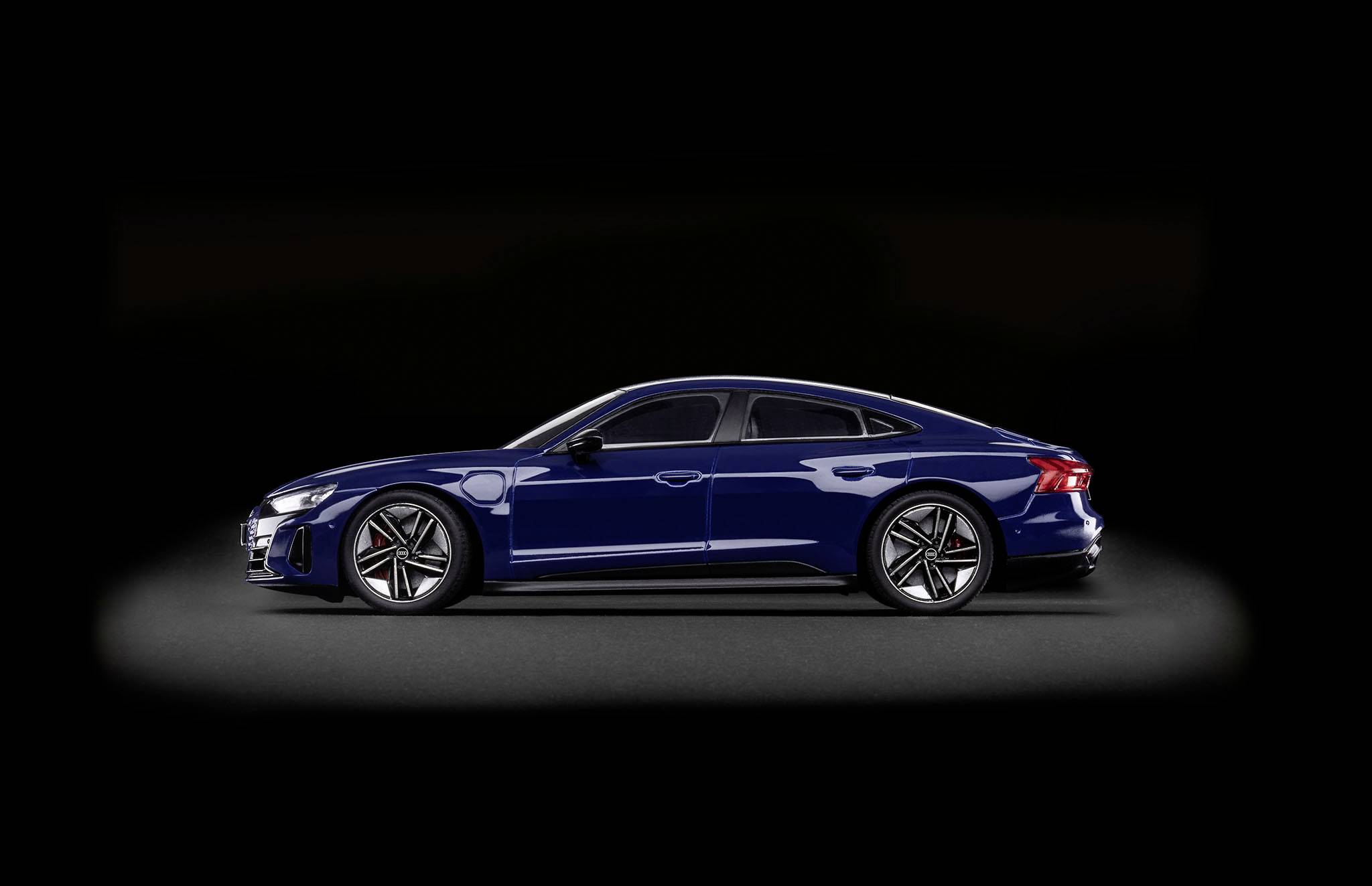 Voiture électrique bleu foncé stationnée sur un fond noir. Design élégant avec des jantes marquantes et des lignes aérodynamiques.