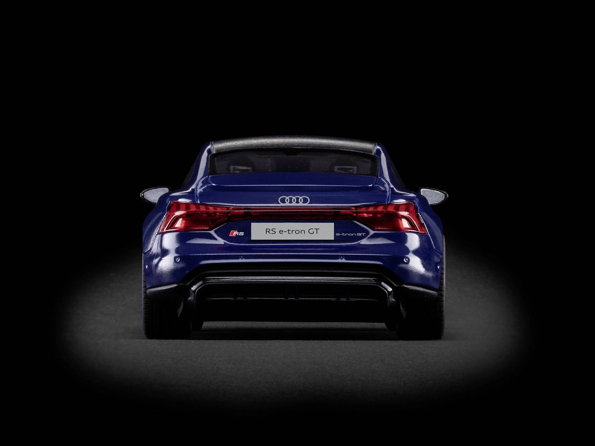 Vue arrière d'une Audi RS e-tron GT bleue sur fond noir, montrant le logo de l'entreprise et les détails des feux arrière.