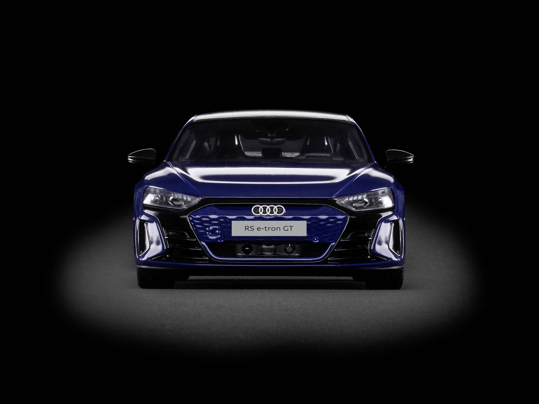 Audi RS e-tron GT en bleu foncé, vue de face sur fond noir, illustrant le design moderne et sportif de cette voiture électrique.